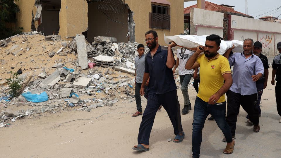 People carry away a body after identifying it among corpses unearthed from a mass grave found in the Nasser Medical Complex in the southern Gaza Strip. - AFP/Getty Images