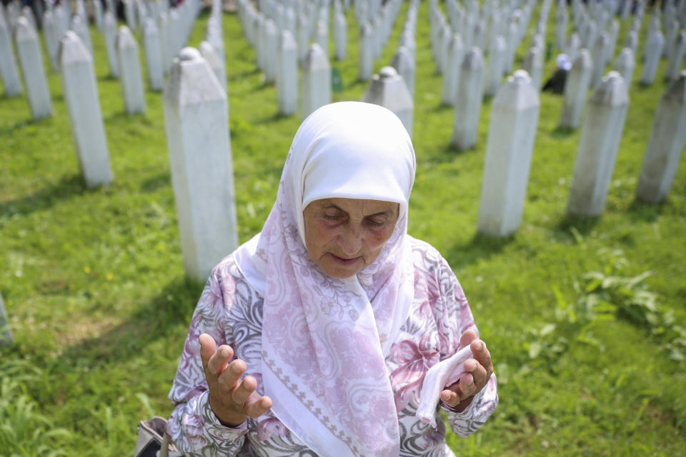 A Bosnian muslim woman prays next to the grave of her relative, victim of the Srebrenica genocide, in Memorial Centre in Potocari, Bosnia, Tuesday, July 11, 2023. Thousands converge on the eastern Bosnian town of Srebrenica to commemorate the 28th anniversary on Monday of Europe's only acknowledged genocide since World War II. (AP Photo/Armin Durgut)
