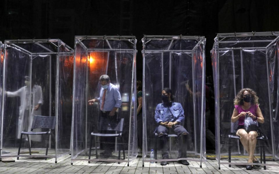 Spectators enter individual plastic cabins as they keep social distance to watch a theatre play in Sao Paulo, Brazil  - Reuters