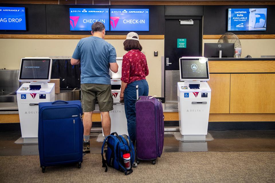 Travelers check in for their flight at a Delta Airlines kiosk in the Asheville Airport July 14, 2023.