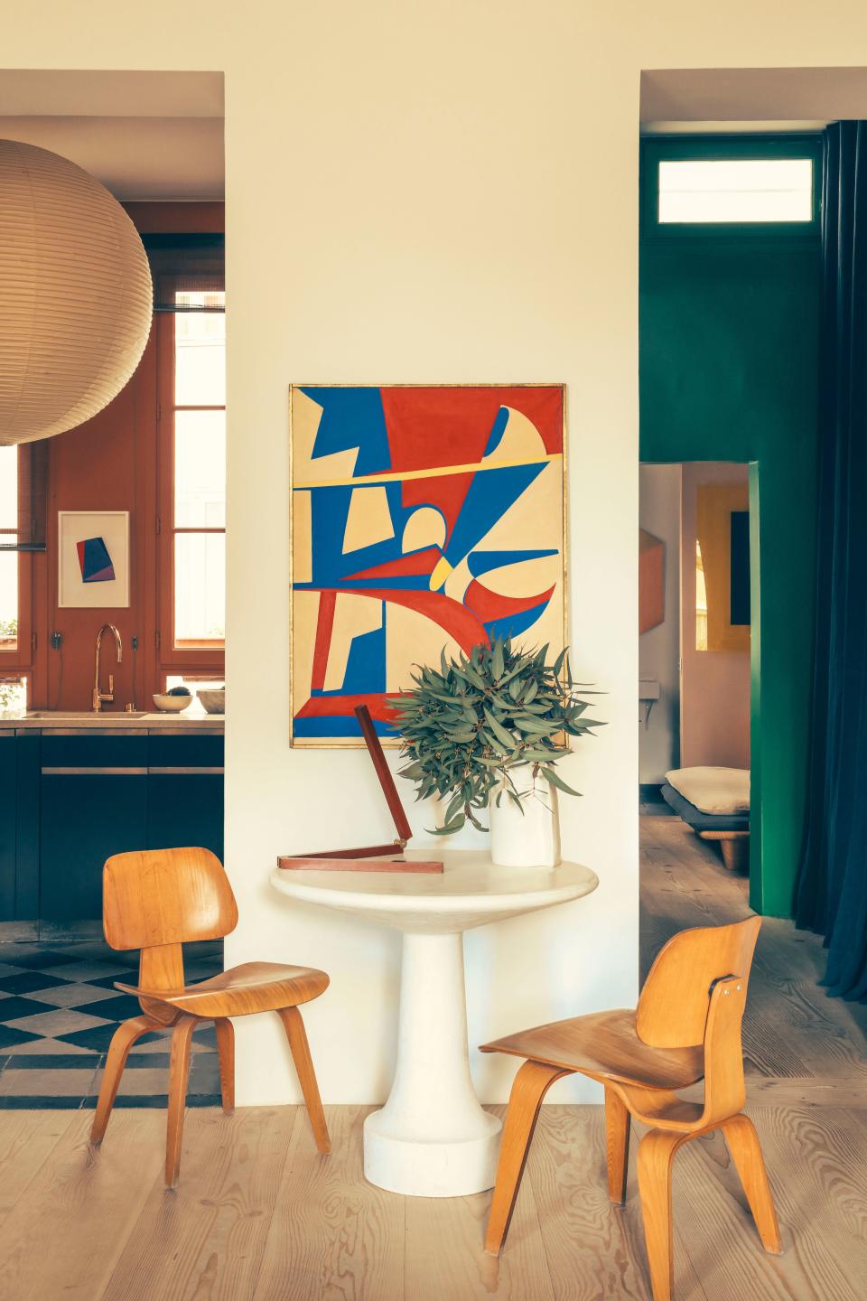 In the salon, a Noguchi lantern hangs to the left and a circa 1960 Italian painting is on the wall. The chairs are LCW by Charles and Ray Eames.