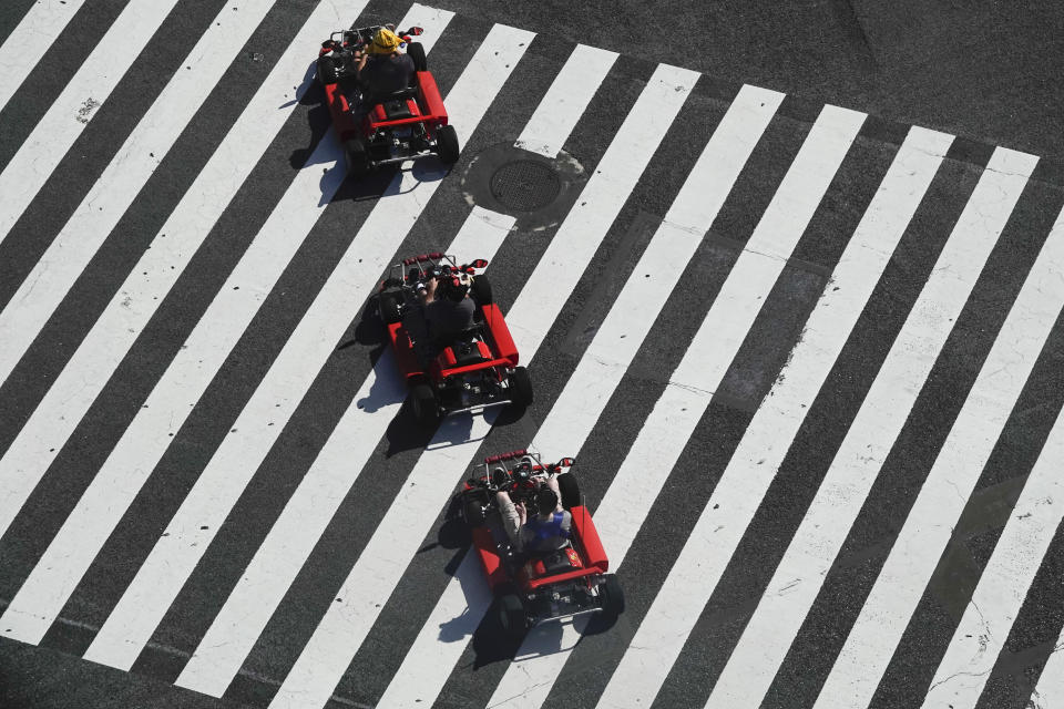 A group of people in go-karts cruise through the Shibuya crossing Thursday, June 13, 2019, in Tokyo. It's not just a crossing. Located just outside Shibuya Station, the scramble crossing is one of the top tourist attractions in Japan. It's so famous that there's an observation deck on the rooftop of a building built to watch the crossing. During rush hour, an estimated 1000 to 2500 people cross the intersection during each traffic light change. (AP Photo/Jae C. Hong)