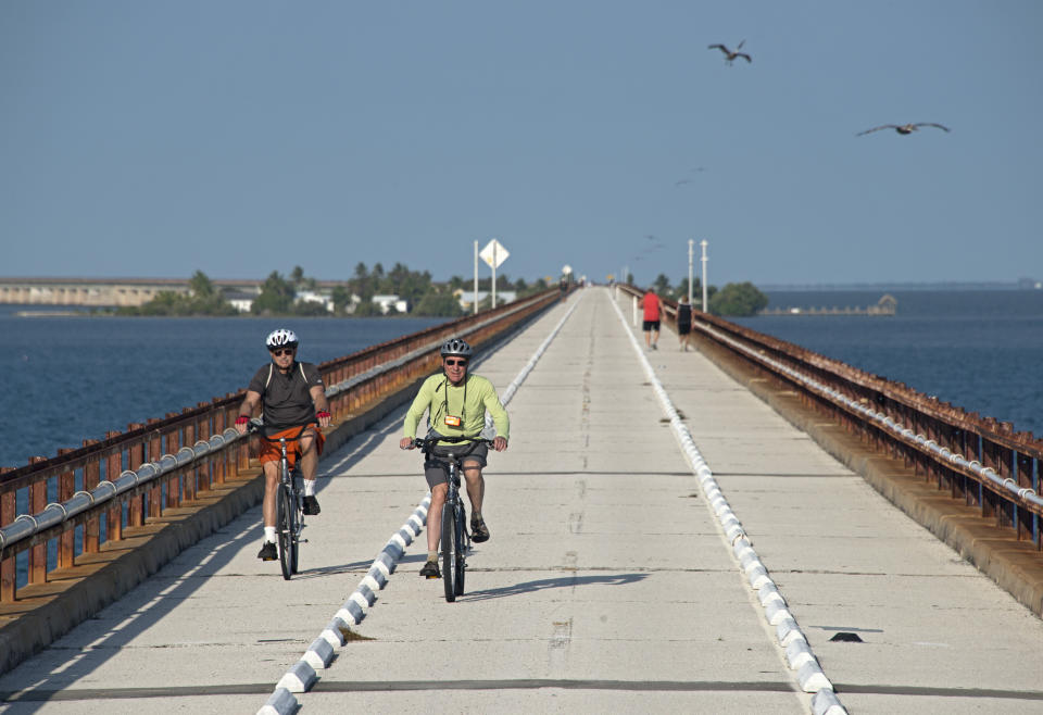 In this photo, provided by the Florida Keys News Bureau bicyclists traverse the historic Seven Mile Bridge in the Florida Keys near Marathon, Fla., Wednesday, March 19, 2014. The Monroe County Commission Wednesday ratified an agreement between the Florida Department of Transportation, the City of Marathon and the county to begin a 30-year, $77 million restoration and maintenance program on a 2.2-mile segment of the century-old span between Marathon and Pigeon Key. The bridge that once supported Henry Flagler's Florida Keys OverSea Railroad was retired in 1982, after a new span opened to vehicular traffic. (AP Photo/Florida Keys News Bureau, Andy Newman)