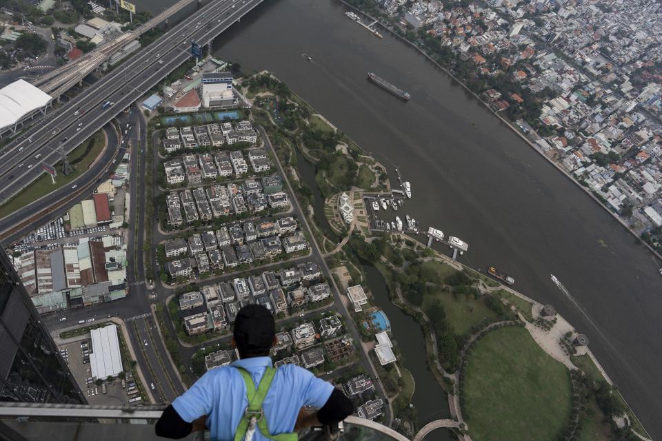 A maintenance worker takes in the view of Ho Chi Minh City, Vietnam, Jan. 21, 2024, as ships cruise along the Saigon River. (AP Photo/Jae C. Hong)