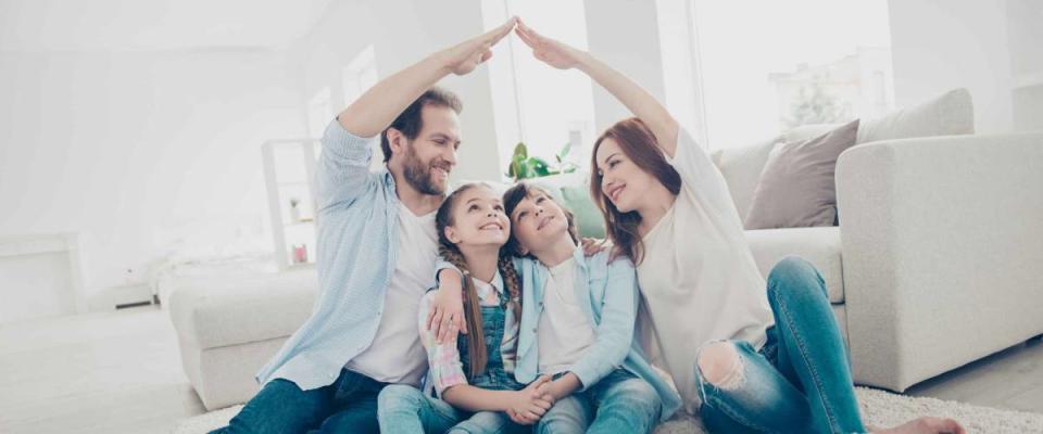 Happy smiling family with parents holding arms up above two kids