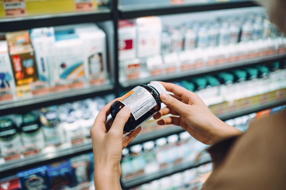 a close up of a person's hands holding a supplement bottle as the person out of the frame reads the label.