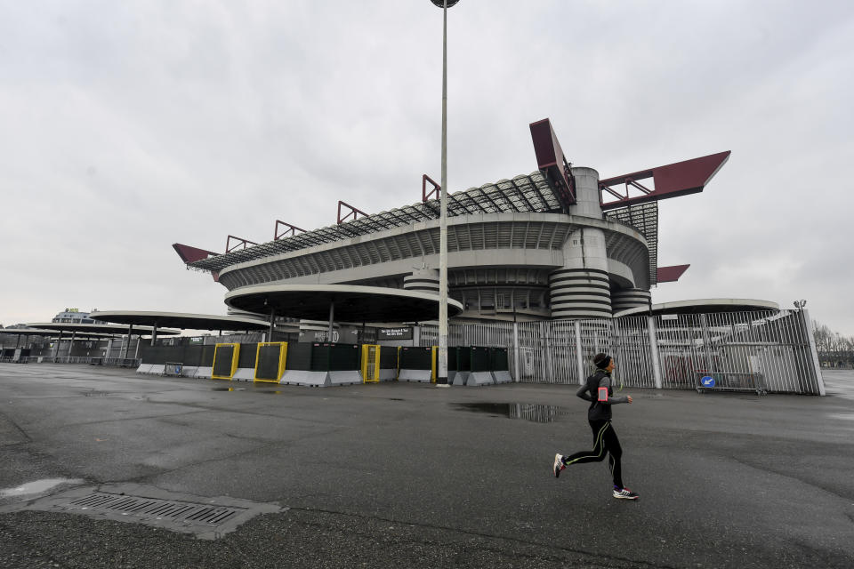 A woman jogs outside San Siro stadium where a Serie A soccer match between AC Milan and Genoa was supposed to take place but was instead postponed to May 13, 2020, in Milan, Italy, Sunday, March 1, 2020. In Lombardy, the hardest-hit region by the spread of the Coronavirus, schools and universities were ordered to stay closed, and sporting events were canceled.(Claudio Furlan/LaPresse via AP)