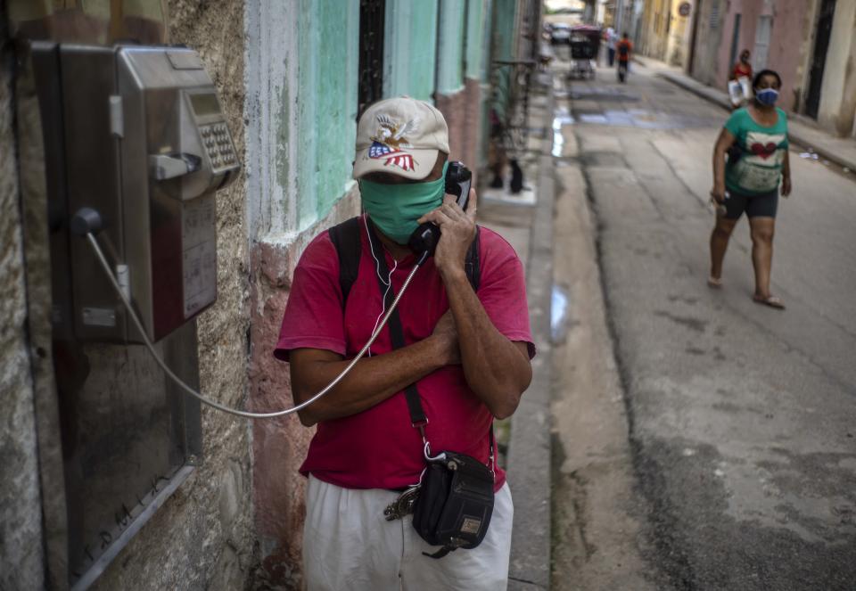 Con una mascarilla protectora en medio de la pandemia del nuevo coronavirus, un hombre habla por un teléfono público en La Habana Vieja, Cuba, el lunes 26 de octubre de 2020. (AP Foto/Ramón Espinosa)