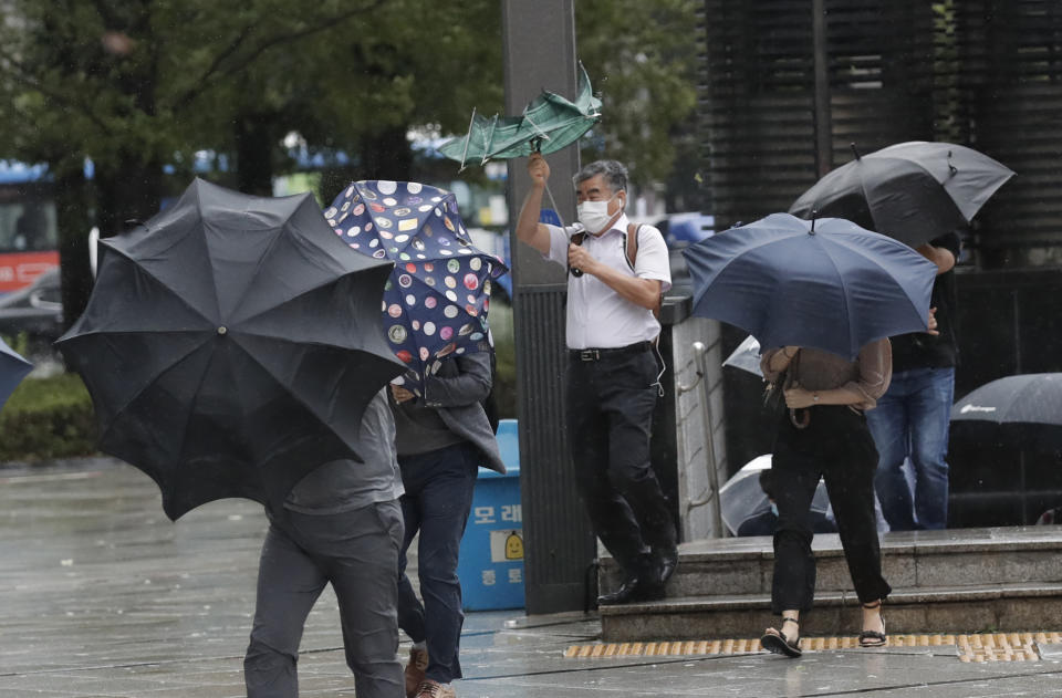 People struggle with their umbrellas against strong wind in downtown Seoul, South Korea, Thursday, Sept. 3, 2020. A powerful typhoon ripped through South Korea’s southern and eastern coasts with tree-snapping winds and flooding rains Thursday, knocking out power to thousands of homes. (AP Photo/Lee Jin-man)