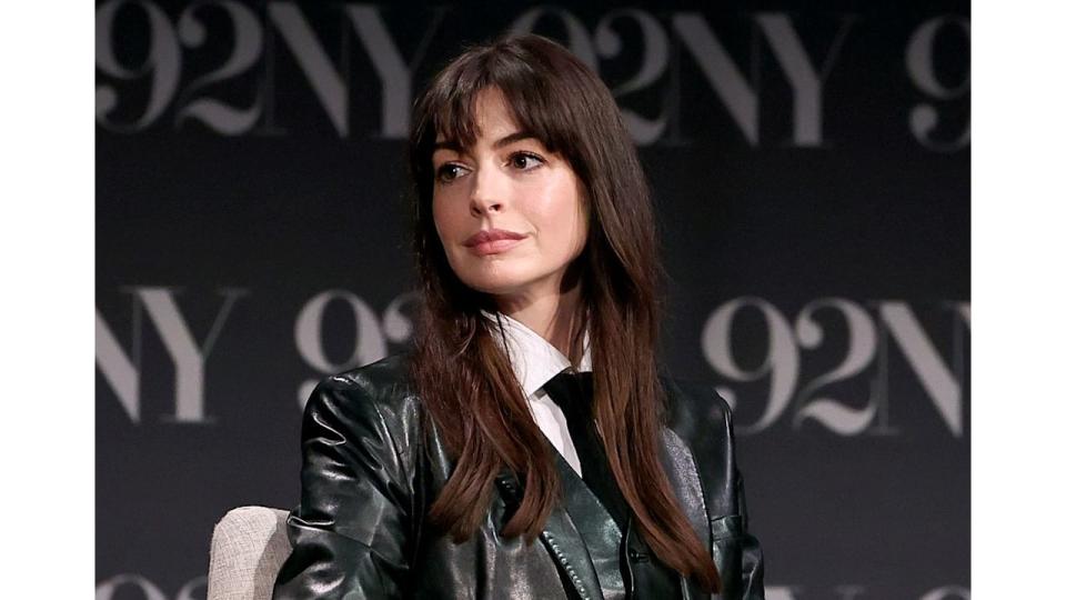 Anne Hathaway in a black leather jacket looking off to the side