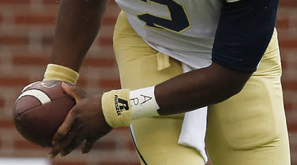 FILE - In this Sept. 21, 2013 file photo, Georgia Tech quarterback Vad Lee (2), wears APU for "All Players United" on his wrist tape, as he works against North Carolina during an NCAA football game in Atlanta. The decision to allow Northwestern football players to unionize raises an array of questions for college sports. Among them, state schools vs. public schools, powerhouse programs vs. smaller colleges (AP Photo/Mike Stewart, File)