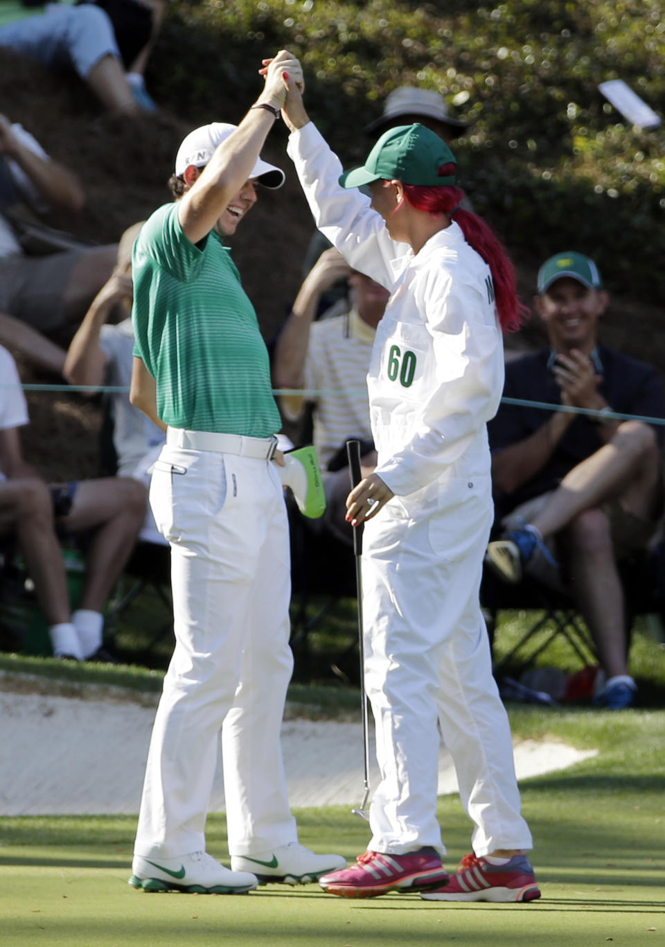 Tennis player Caroline Wozniacki high fives with her fiancee Rory McIlroy, of Northern Ireland, after Wozniacki putted on the ninth hole during the par three competition at the Masters golf tournament Wednesday, April 9, 2014, in Augusta, Ga. (AP Photo/David J. Phillip)