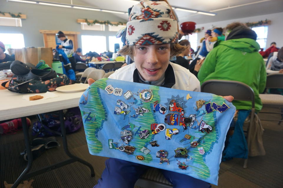 Cedar Ruckel, an Anchorage skier and member of Team Alaska, shows his collection of pins from visiting delegations to the 2024 Arctic Winter Games during a break in competition March 14 at Government Peak Recreation Area. (Photo by Yereth Rosen/Alaska Beacon)