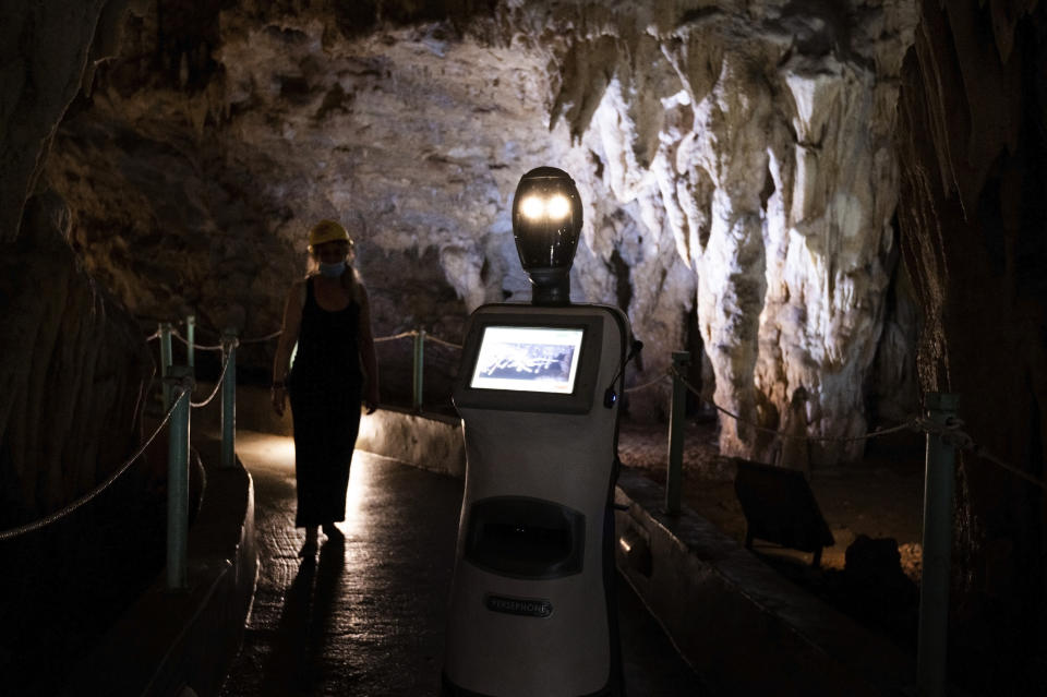 Persephone guides the visitors inside Alistrati cave, about 135 kilometers (84 miles) northeast of Thessaloniki, Greece, Monday, Aug. 2, 2021. Persephone, billed as the world's first robot used as a tour guide inside a cave, has been welcoming visitors to the Alistrati cave, since mid-July. (AP Photo/Giannis Papanikos)