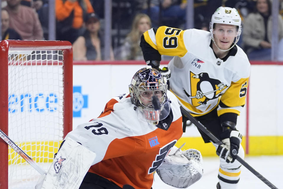 Philadelphia Flyers' Carter Hart, left, and Pittsburgh Penguins' Jake Guentzel watch the puck during the first period of an NHL hockey game, Monday, Jan. 8, 2024, in Philadelphia. (AP Photo/Matt Slocum)