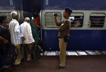 A railway police official films commuters as they board a passenger train at a railway station in Kolkata February 25, 2015. REUTERS/Rupak De Chowdhuri