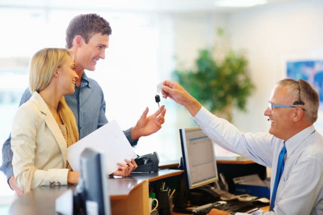 CXDWGB Senior employee handing a smiling couple the key to their car rental Car; hire; rental; couple; vehicle; company; adult;