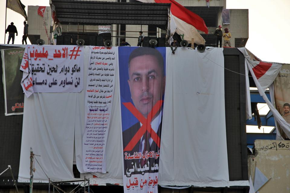 Protesters hang a big poster with a defaced picture of Asaad al-Eidani, Iran-backed parliamentary bloc's nominee for the post of the prime minister and Arabic that reads "rejected by the people," in Tahrir Square during anti-government demonstrations in Baghdad, Iraq, Thursday, Dec. 26, 2019. Iraq's president refused Thursday to designate Asaad al-Eidani for the post of prime minister after he was rejected by anti-government protesters and said he was ready to submit his resignation to Parliament. (AP Photo/Khalid Mohammed)