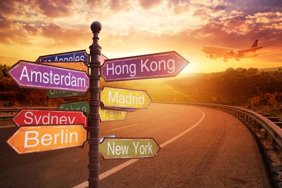 Several boards on a road sign with names of different places on them pointing in various directions.