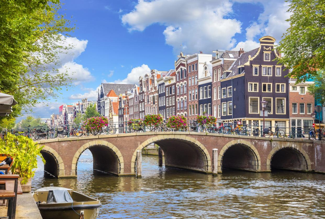 Amsterdam downtown - Amstel river, old houses and a bridge. Nice view of the famous city of Amsterdam. Travel to Europe. Amsterdam, Holland, Netherlands, Europe.