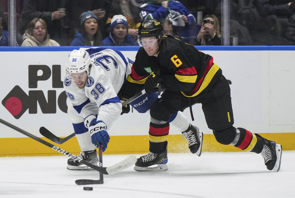 Vancouver Canucks' Brock Boeser (6) checks Tampa Bay Lightning's Brandon Hagel (38) during the second period of an NHL hockey game in Vancouver, B.C., on Tuesday, Dec. 12, 2023. (Darryl Dyck/The Canadian Press via AP)