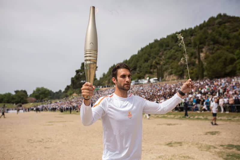 The first torchbearer, 2020 Olympic rowing champion Stefanos Ntouskos, runs with the Olympic torch during the lighting ceremony for Paris 2024 on the site of Ancient Olympia. Socrates Baltagiannis/