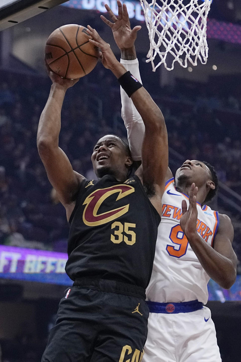 Cleveland Cavaliers forward Isaac Okoro (35) shoots in front of New York Knicks guard RJ Barrett (9) during the first half of an NBA basketball game Tuesday, Oct. 31, 2023, in Cleveland. (AP Photo/Sue Ogrocki)