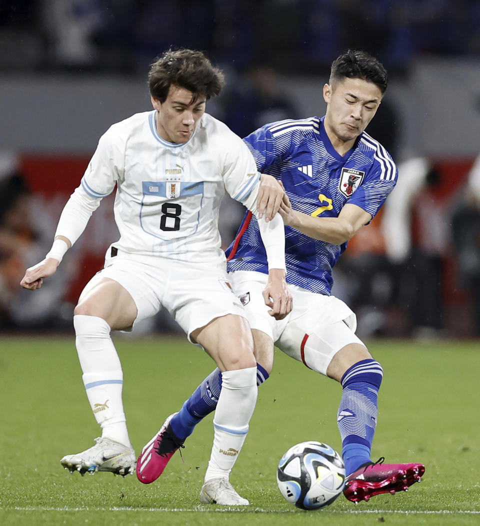 Uruguay's Facundo Pellistri, left, and Japan's Yukinari Sugawara battle for the ball in the first half of their friendly soccer match at the National Stadium in Tokyo, Friday, March 24, 2023. (Kyodo News via AP)