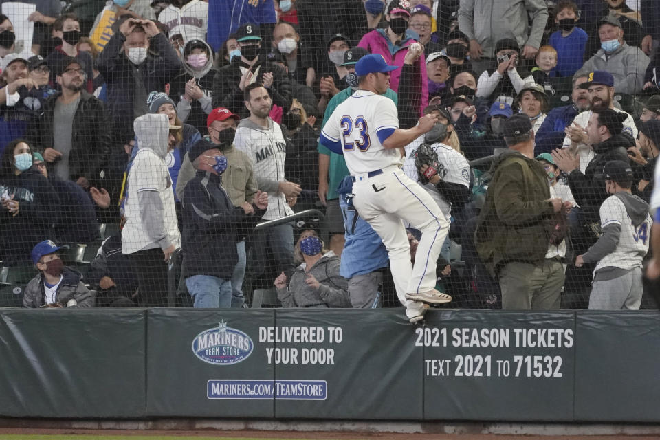 Seattle Mariners first baseman Ty France (23) stands on the wall after a fan on the other side of the safety net caught a pop-up foul hit by Los Angeles Angels' Juan Lagares during the sixth inning of a baseball game, Sunday, Oct. 3, 2021, in Seattle. (AP Photo/Ted S. Warren)