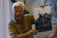 Famed Vietnamese war photographer Dinh Quang Thanh, 80, holds one of his photographs showing a crashed US helicopter left atop a building on April 30, 1975, during an interview with AFP at his home in Hanoi