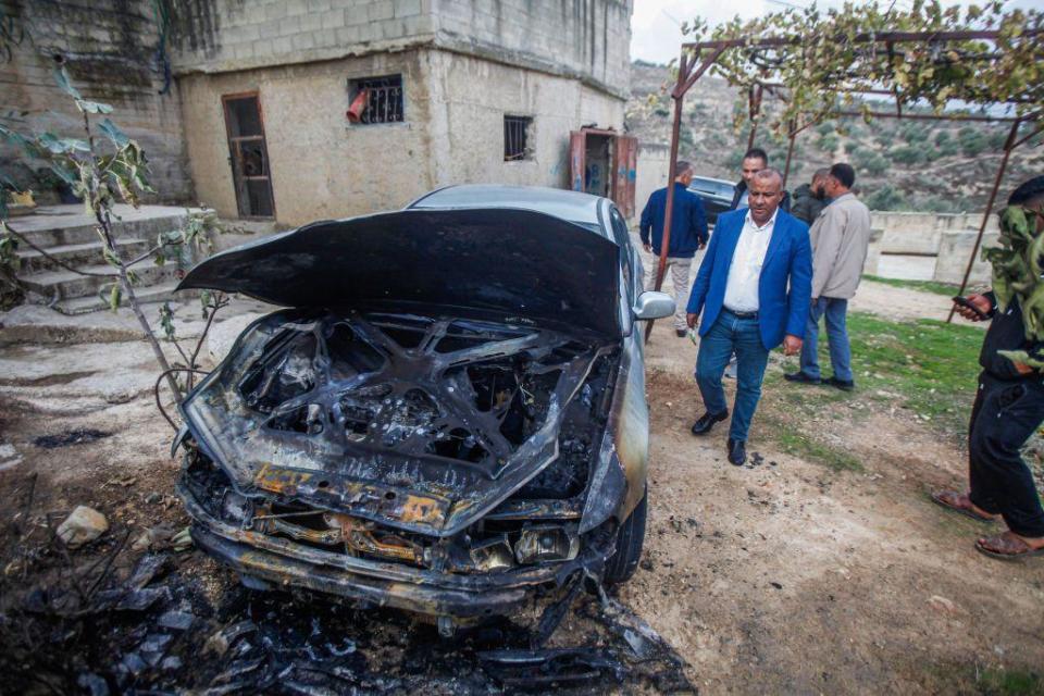 Palestinos observan uno de sus vehículos presuntamente incendiado por colonos israelíes en Cisjordania.