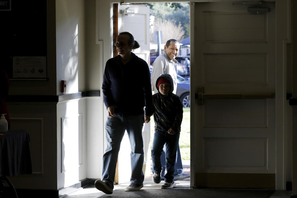 The door is held open for attendants arriving for the first service, held in the Fellowship Hall at the Westminster United Methodist Church Sunday, Dec. 12, 2021, in Houston. The church holds two Sunday services. The first is a looser, more contemporary service with an electric band that is better attended by families with children. The second is the traditional service held in the sanctuary. (AP Photo/Michael Wyke)