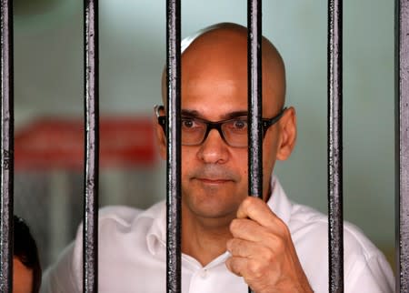 FILE PHOTO: Canadian teacher Neil Bantleman looks out from a holding cell to speak with supporters before the start of his trial at a South Jakarta court in Jakarta