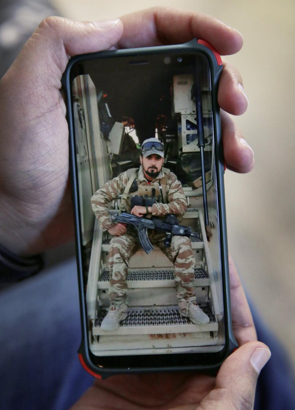 Kaihan shows a cellphone photo of himself from when he was in the Afghan National Army.