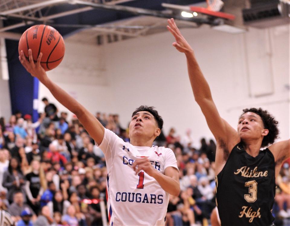 Andrew Gonzalez (1) drives to the basket as Abilene High&#39;s Hayden Williams (3) defends in the first quarter. Cooper beat the Eagles 56-46 in the nondistrict game Friday, Dec. 17, 2021, at Cougar Gym.