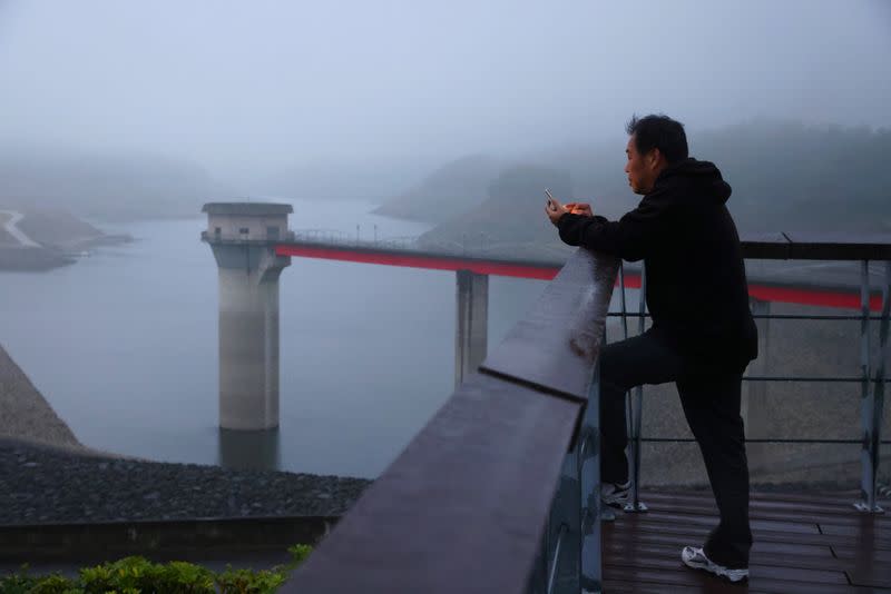 Man uses his phone in front of the Baoshan second reservoir amid low water levels during an island-wide drought, in Hsinchu, Taiwan