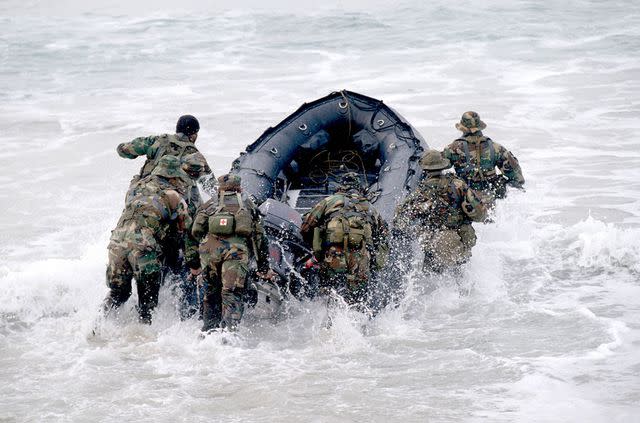 <p>Greg Mathieson/Mai/Getty</p> Stock image of Navy SEALS pushing a boat in the water