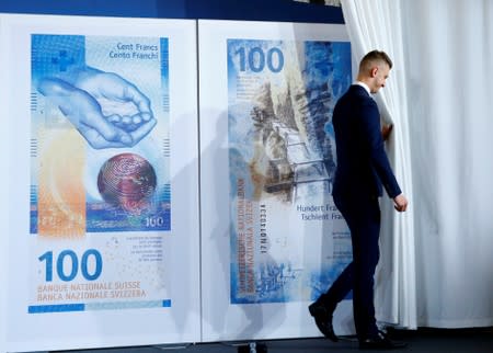 An employee of the Swiss National Bank unveils the new 100 franc banknote during a news conference in Bern