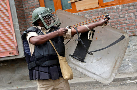 Apoliceman uses a slingshot during clashes with demonstrators following a protest in Srinagar against the recent killings in Kashmir, August 11, 2016. REUTERS/Danish Ismail