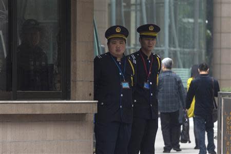 A police officer (L) and security officers stand guard outside the Southern Weekly newspaper office in the southern Chinese city of Guangzhou January 7, 2014. REUTERS/Tyrone Siu