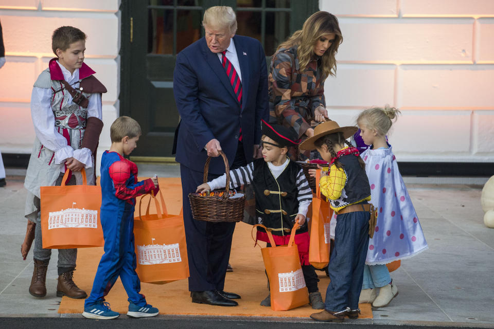 President Donald Trump and first lady Melania Trump give candy to children during a Halloween trick-or-treat event on the South Lawn of the White House which is decorated for Halloween, Monday, Oct. 28, 2019, in Washington. (AP Photo/Alex Brandon)