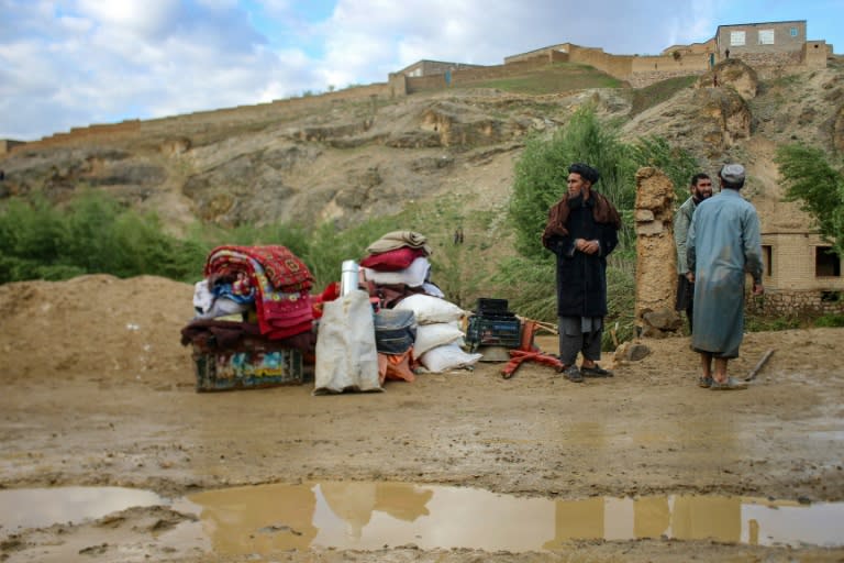 Des Afghans se tiennent près de leurs biens à proximité d'une maison endommagée par des inondations meurtrières à Firozkoh, dans la province de Ghor, le 18 mai 2024 (-)