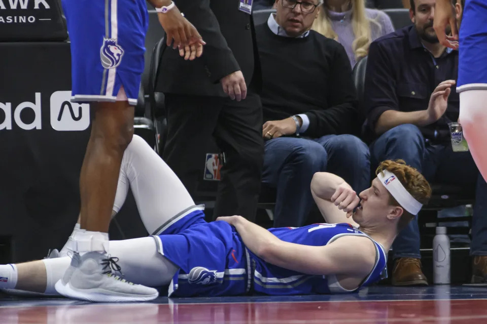 Sacramento Kings guard Kevin Huerter lies on the floor after an injury to his left arm during the first half of an NBA basketball game against the Memphis Grizzlies in Sacramento, Calif., Monday, March 18, 2024. (AP Photo/Randall Benton)