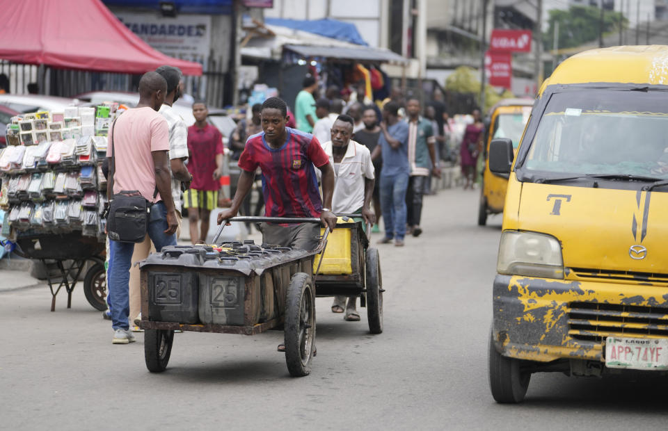A man pushes a cart with jerrycans of water along the streets of Lagos, Nigeria, Tuesday Sept. 5, 2023. (AP Photo/Sunday Alamba)