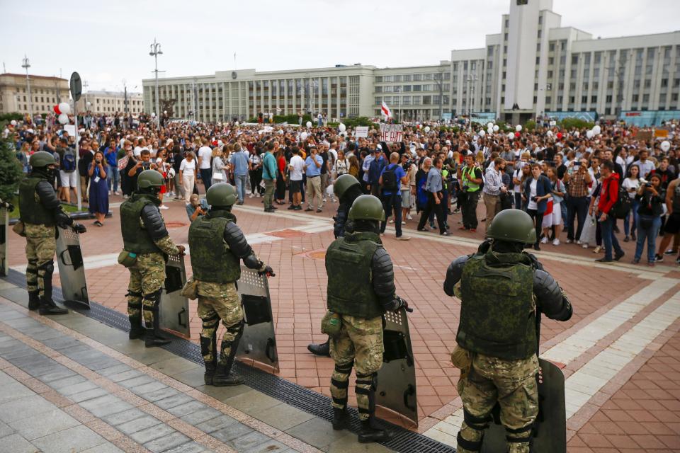 People gather in front of soldiers guarding the Belarusian Government building during a rally in Minsk, Belarus, Friday, Aug. 14, 2020. Some thousands of people have gathered in the centre of the Belarus capital, Minsk, in a show of anger over a recent brutal police crackdown on peaceful protesters that followed a disputed presidential election.(AP Photo/Sergei Grits)