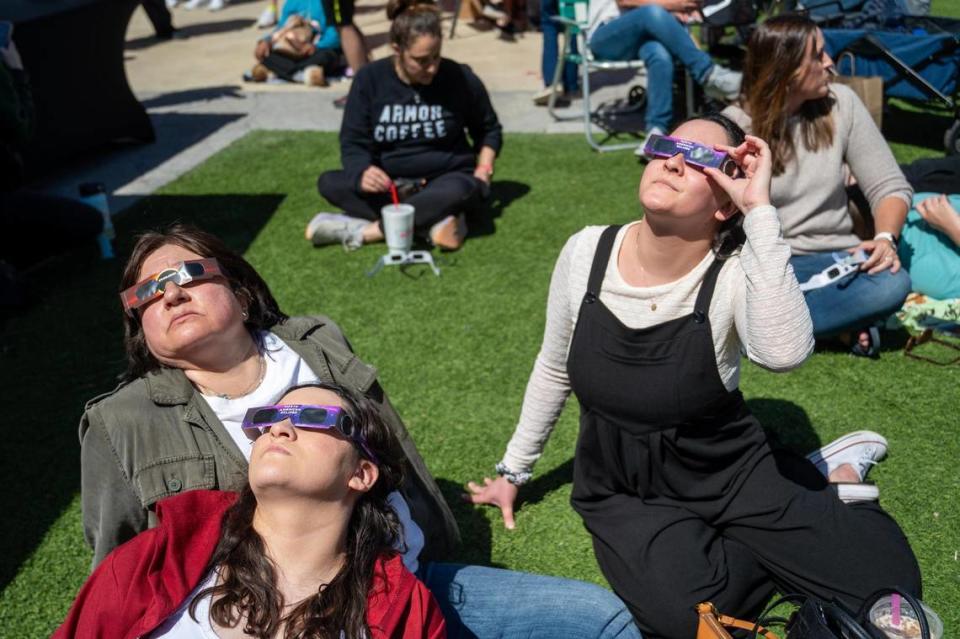 Natalia Arellano, her mother, Gaby Luna, left, and Melanie Arellano, right, all of Kansas City, Kansas, watched the solar eclipse together on Luna’s birthday during a watch party at The Lawn at Legends Outlets on Monday, April 8, 2024, in Kansas City, Kansas. A solar eclipse happens when the Moon passes between the Sun and Earth, blocking the face of the Sun.