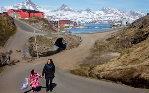 A woman and child hold hands as they walk on the street in the town of Tasiilaq, Greenland - Credit: Lucas Jackson/Reuters