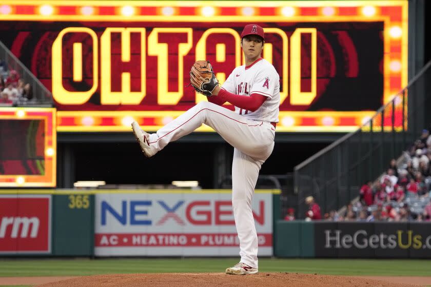 Ohtani winds up to throw the ball from the mound. A sign in the background says his name