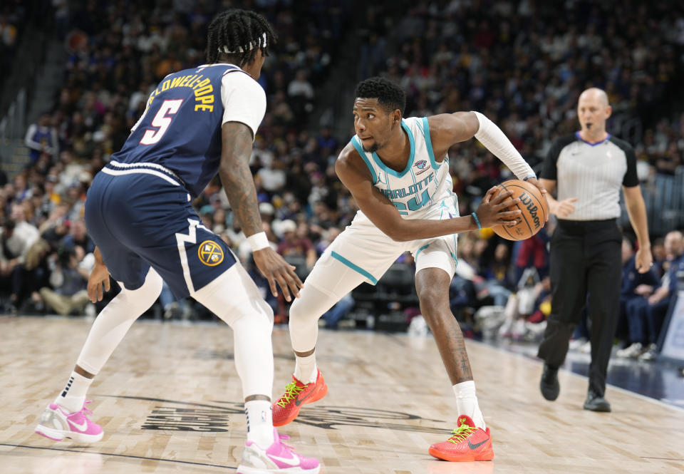 Charlotte Hornets forward Brandon Miller, right, looks to pass the ball as Denver Nuggets guard Kentavious Caldwell-Pope defends (5) in the second half of an NBA basketball game Monday, Jan. 1, 2024, in Denver. (AP Photo/David Zalubowski)