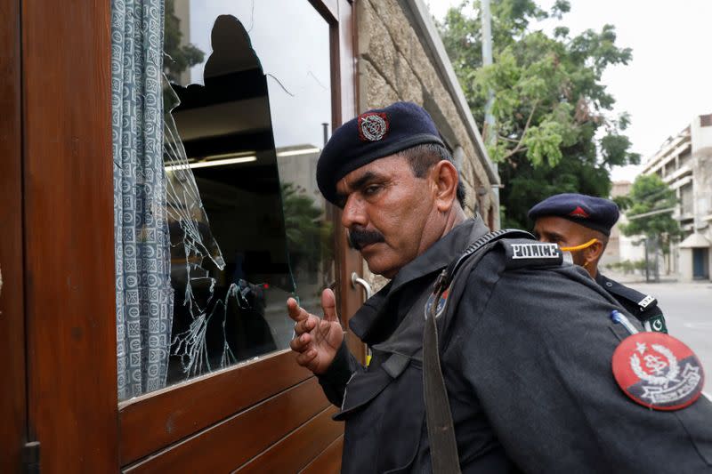 Police officers gather at the damaged security post of the Pakistan Stock Exchange building after an attack in Karachi